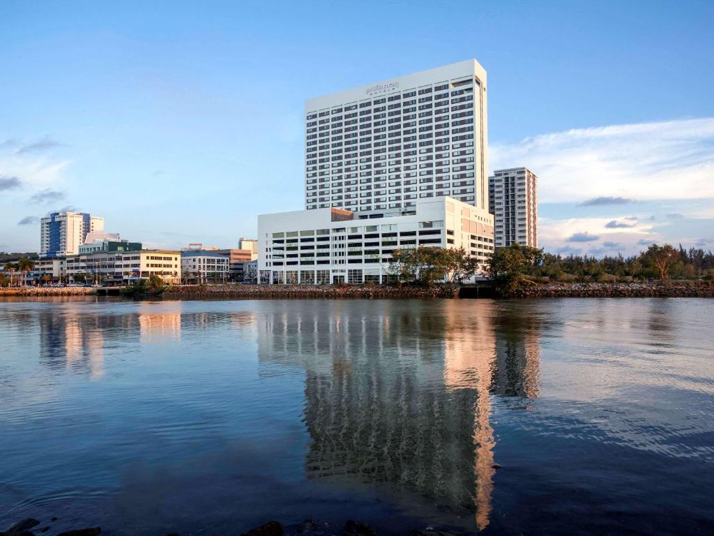 um horizonte da cidade com um grande edifício e um rio em Pullman Miri Waterfront em Miri