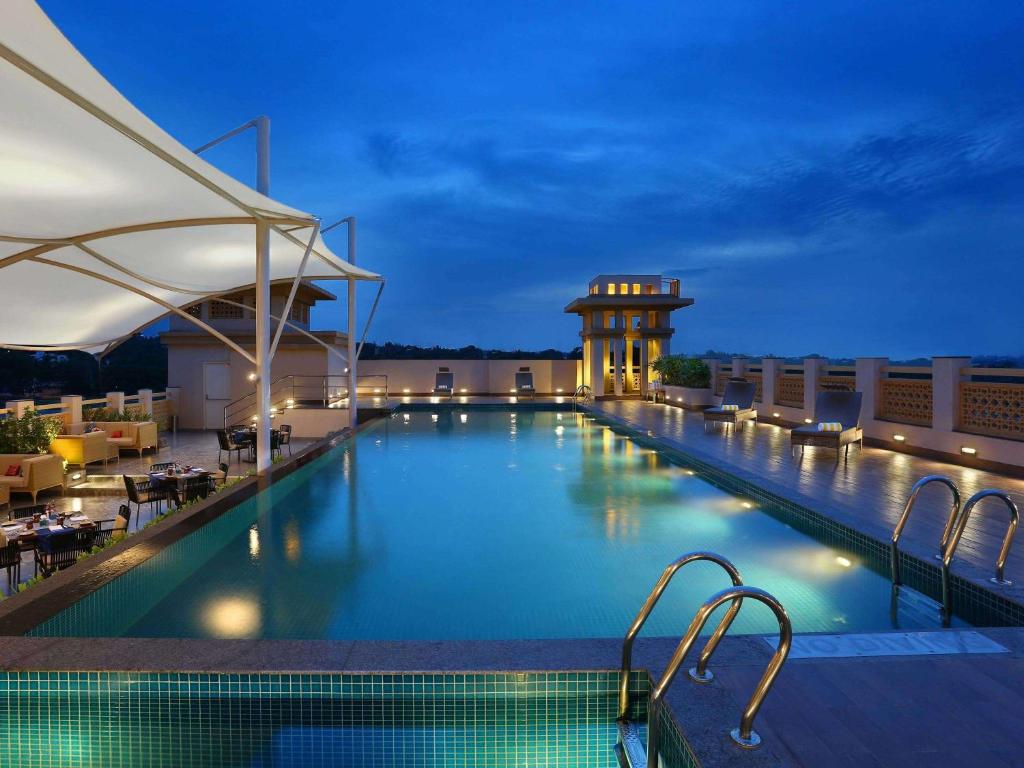 - une piscine sur le toit d'un hôtel la nuit dans l'établissement Grand Mercure Mysore - An Accor Brand, à Mysore