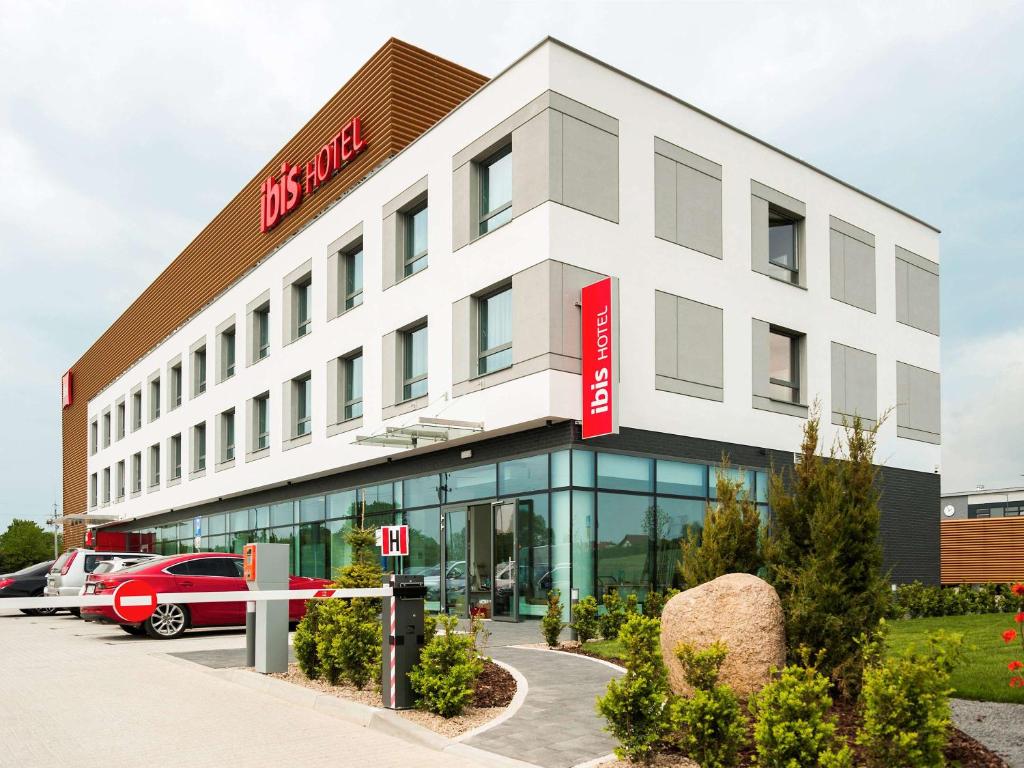 a large white building with a red sign on it at Ibis Poznan Polnoc in Suchy Las