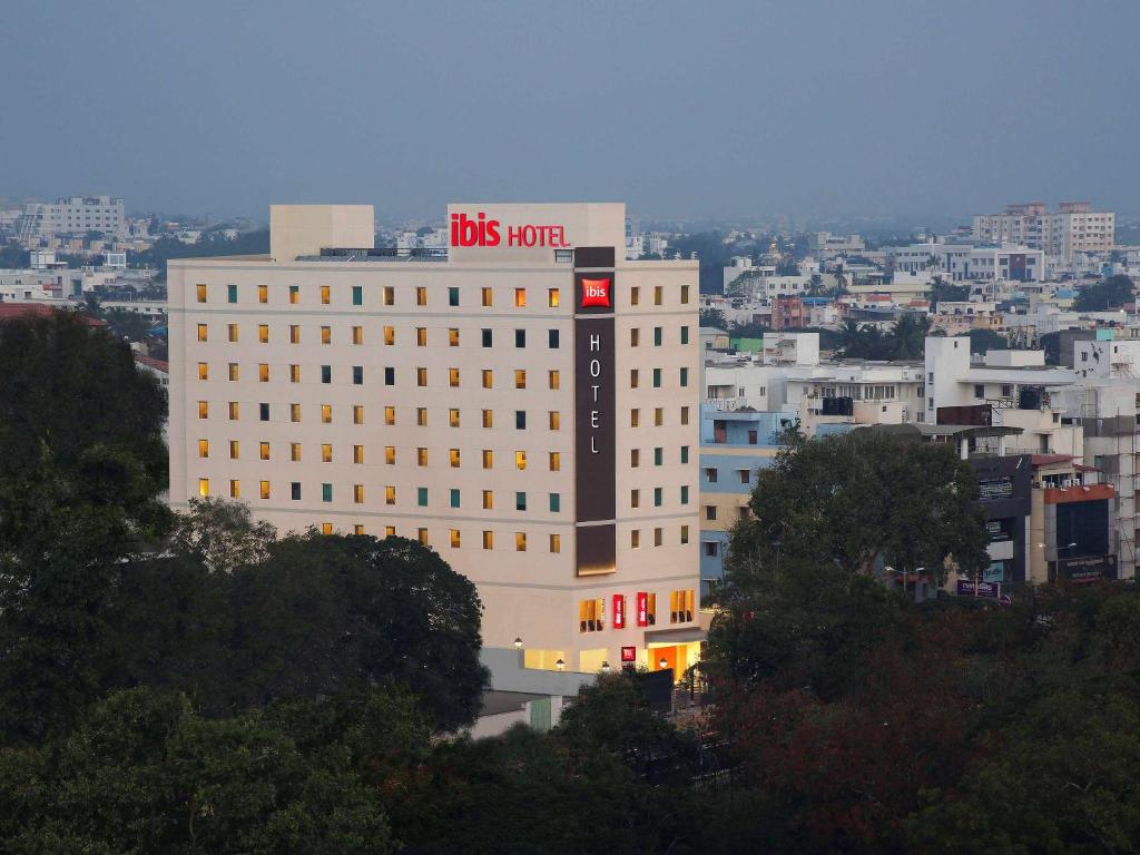 ibis Coimbatore City Centre - An Accor Brand في كويمباتور: مبنى أبيض كبير مع علامة على مستودع الحافلات
