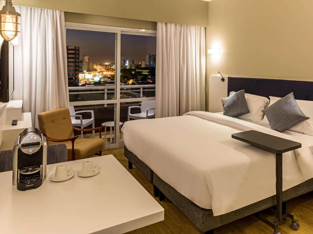 a hotel room with a large bed and a balcony at Mercure Sao Bernardo Do Campo in São Bernardo do Campo