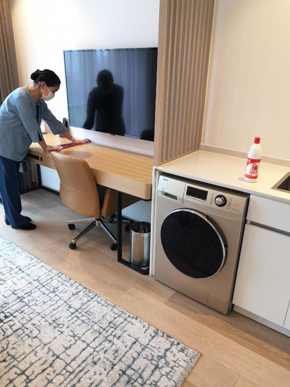 a woman standing at a desk with a microwave at Sincere Residence Changfeng - Changfeng Ecological Business District - Near Exit 3 of Changfeng Park Station on Subway Line 15 in Shanghai