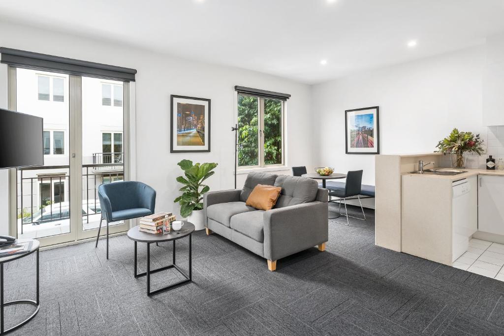 a living room with a couch and a kitchen at Quest Prahran in Melbourne