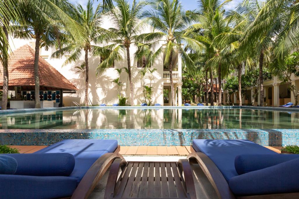
a patio with a pool, chairs, and tables at Anantara Hoi An Resort in Hoi An
