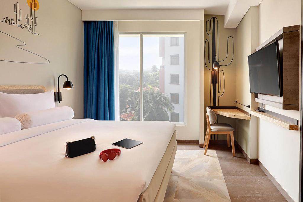 una camera d'albergo con letto e finestra di ibis Styles Jakarta Simatupang a Giacarta