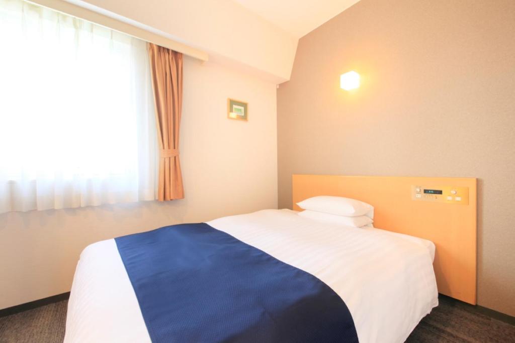 a bedroom with a blue and white bed with a window at Hotel Grand City in Tokyo