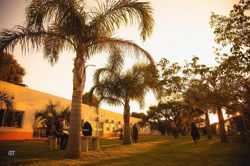 a group of people sitting on a bench under a palm tree at Pousada Costa Doce in Rio Grande