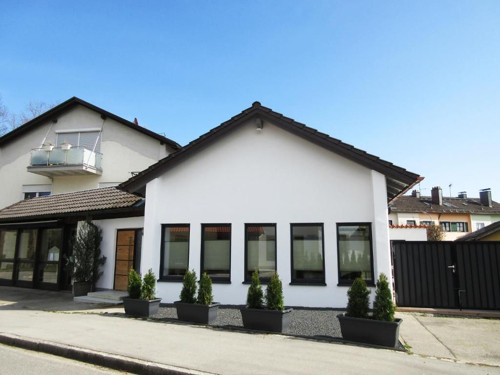 ein weißes Haus mit Topfpflanzen davor in der Unterkunft Ferienhaus Strandbadallee in Waging am See