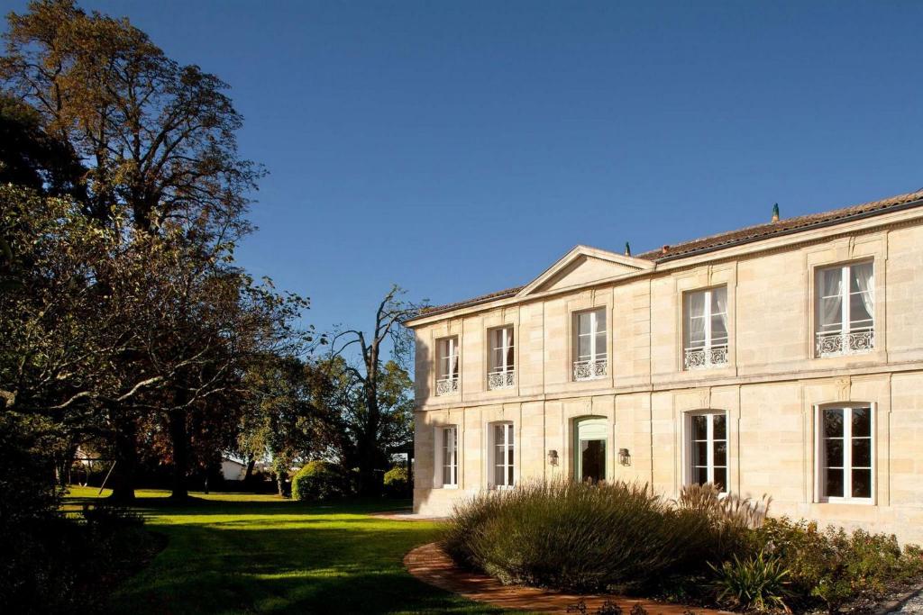 um grande edifício de pedra com árvores e relva em Château Ormes de Pez em Saint-Estèphe