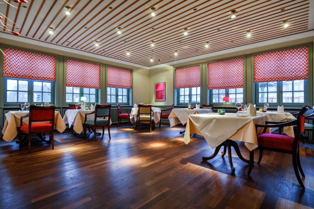 a dining room with tables and chairs and windows at Hotel Stadt Hamburg in Westerland
