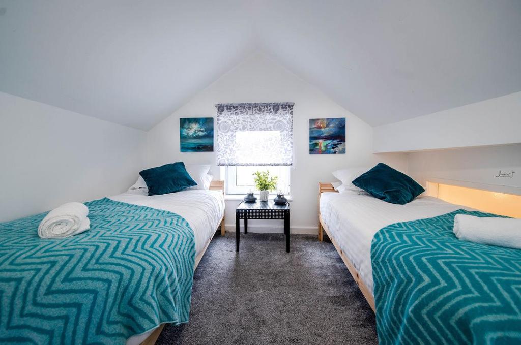 2 camas en una habitación con ventana en Apartment 2 Broadhurst Court sleeps 6, minutes from town centre & trains, en Stockport