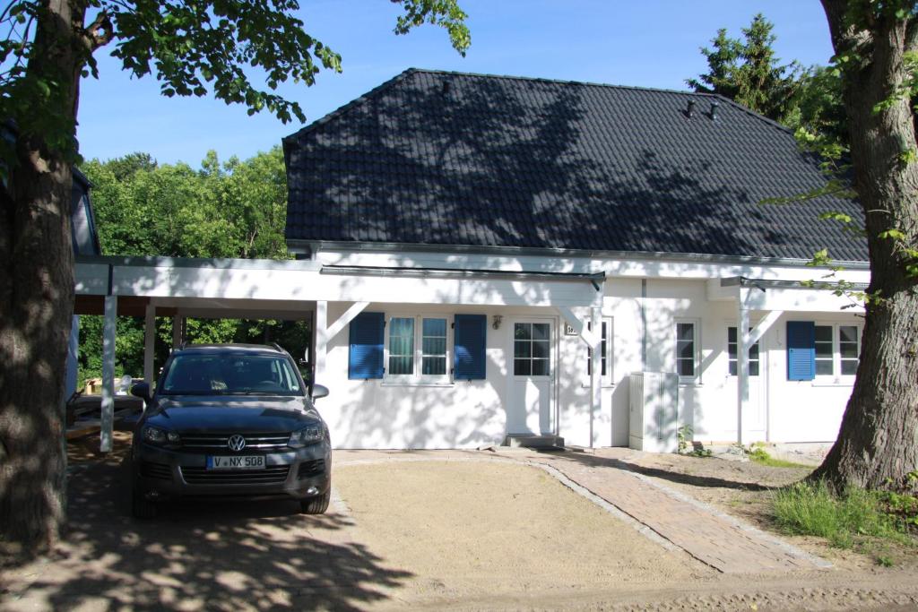 a car parked in front of a white house at Haus Sturmschwalbe in Ummanz