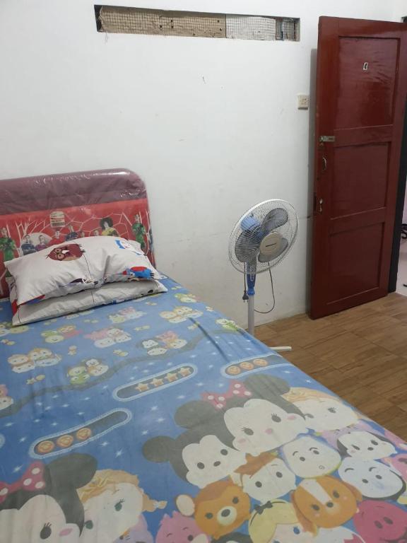 a bedroom with a mickey mouse bedspread and a fan at Homestay Mas Arjuna - Female Only in Bagongsabrangan