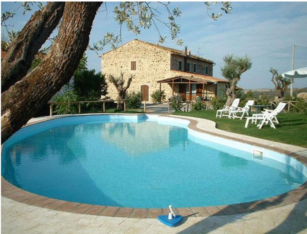 una grande piscina blu di fronte a una casa di Poggio Mario a Saturnia