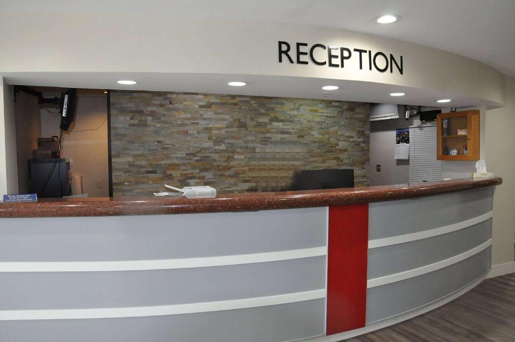 a reception counter in a office with a brick wall at Ramada by Wyndham Abbotsford in Abbotsford