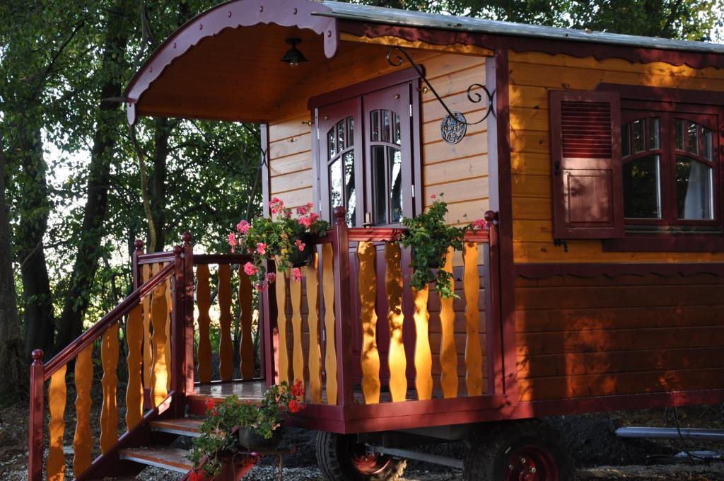 Casa pequeña de madera con porche y escaleras en Gite Insolite "La Roulotte des Elfes", Au Milieu de Nulle Part, en Outines