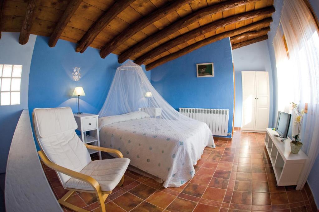 a bedroom with a bed and a chair and a tv at Casa Rural FuenteVieja in La Mata de los Olmos