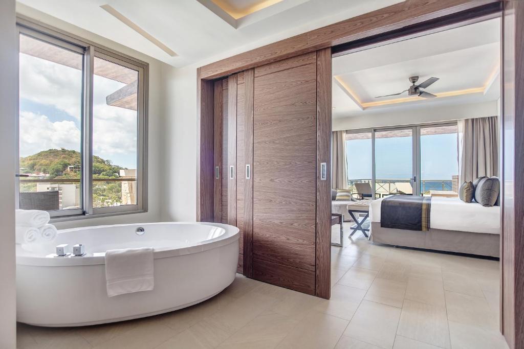 Ocean and landscape view from suite balcony with soaking tub in foreground.