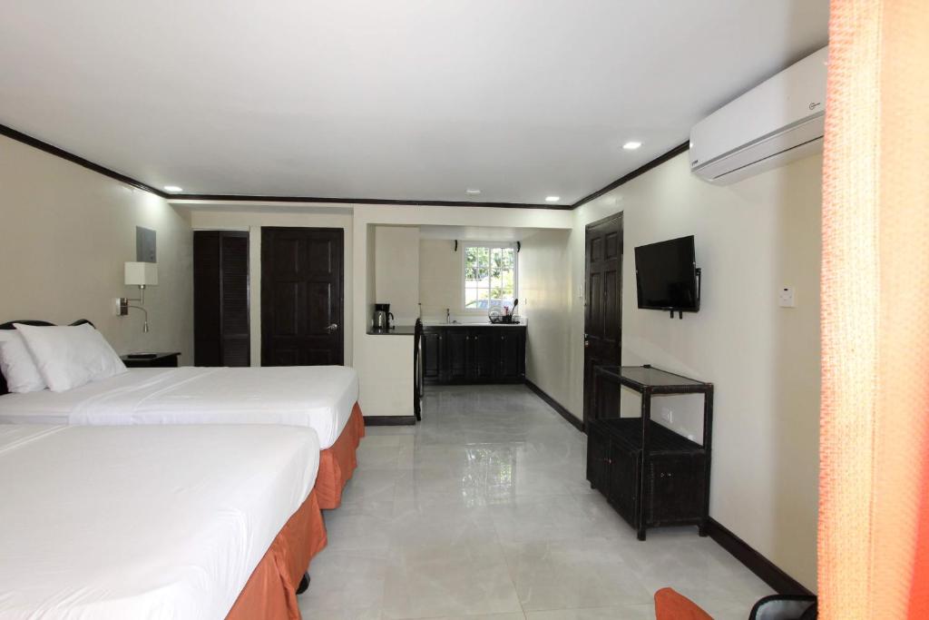 a hotel room with two beds and a television at Sand and Blue Seas in Negril