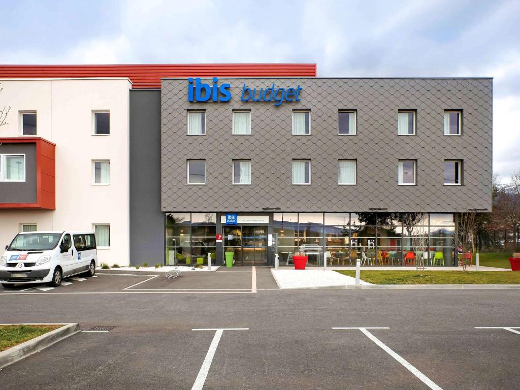 un bâtiment avec une camionnette garée dans un parking dans l'établissement ibis budget Geneve Saint Genis Pouilly, à Saint-Genis-Pouilly