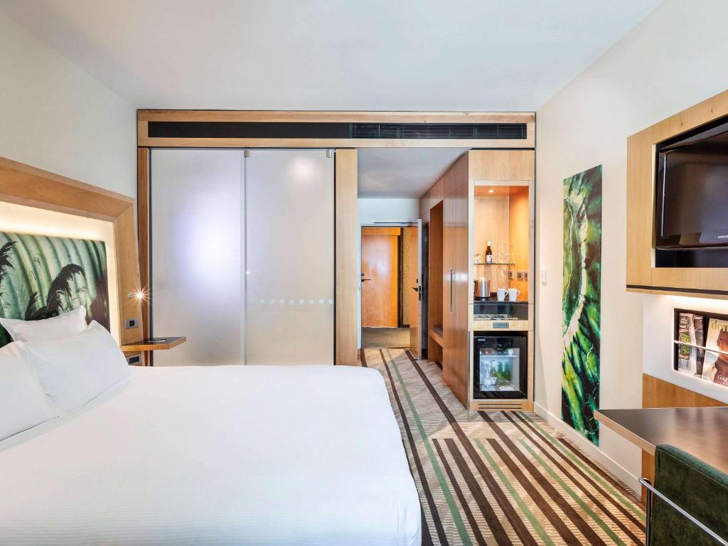 a hotel room with a bed and a flat screen tv at Novotel Auckland Airport in Auckland