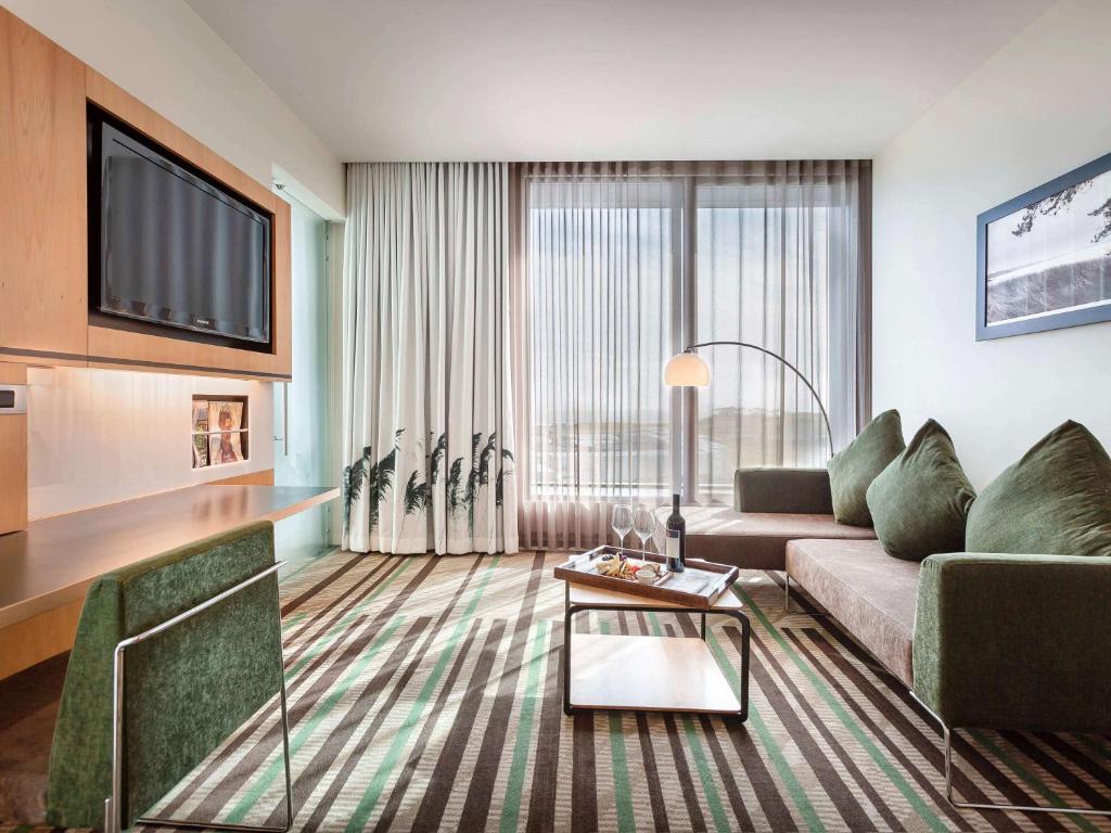 a living room with a couch and a tv at Novotel Auckland Airport in Auckland