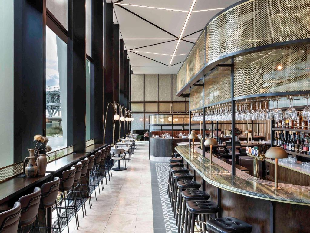 a restaurant with a bar with chairs and tables at Novotel Auckland Airport in Auckland