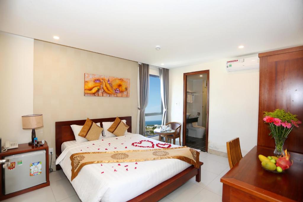 una camera con un grande letto e una scrivania e una camera di Son Tra Green Hotel & Apartment a Da Nang