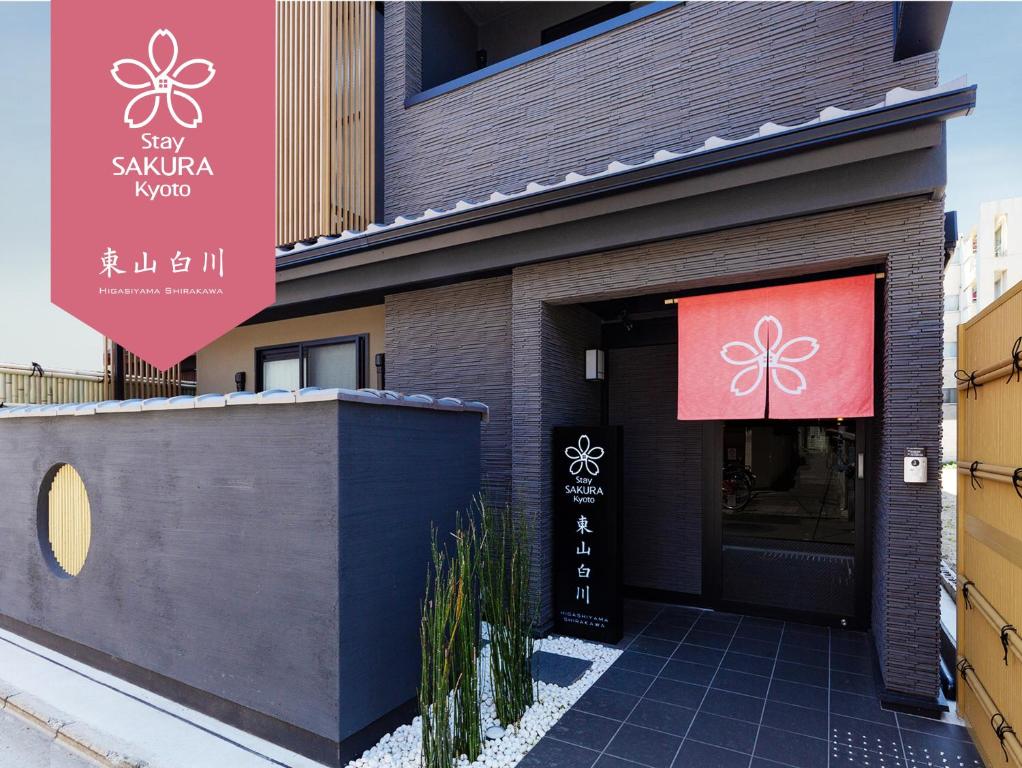 un restaurant avec un panneau rouge sur le côté d'un bâtiment dans l'établissement Stay SAKURA Kyoto Higashiyama Shirakawa, à Kyoto