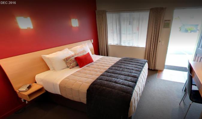 ハミルトンにあるパーク ビュー モーター ロッジの赤い壁のベッドルーム1室(大型ベッド1台付)