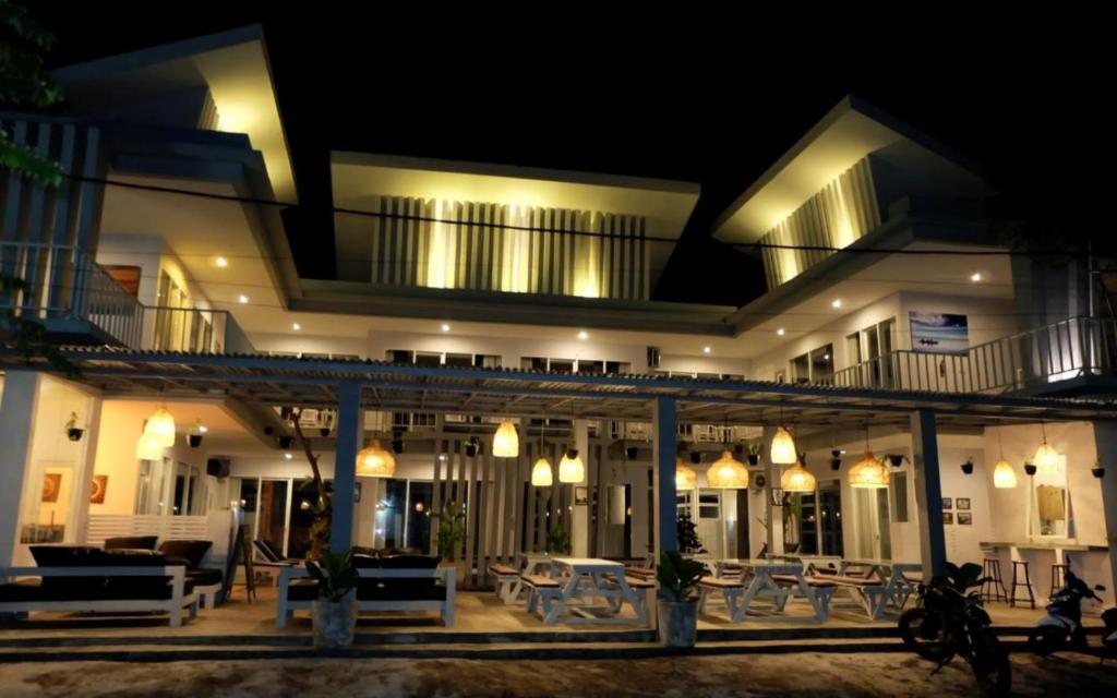 Pom Pom's Bali Apartments في كيروبوكان: مبنى كبير به طاولات وكراسي في الليل