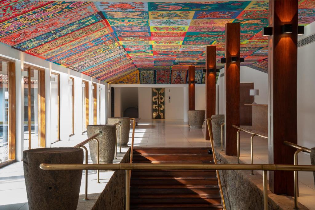 a room with a colorful ceiling with a table and chairs at Cinnamon Bentota Beach - Signature Selection in Bentota