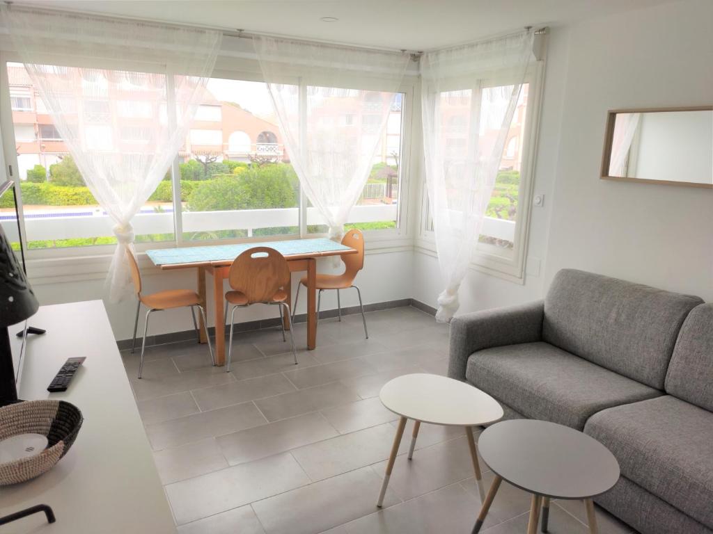 Una sala de estar con un sofá, una mesa y sillas. en Les Soleillades - Plage, piscine, parking!, en Palavas-les-Flots