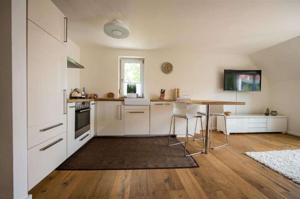 a kitchen with white cabinets and a wooden table at City Center Apartments in Kirchheim unter Teck