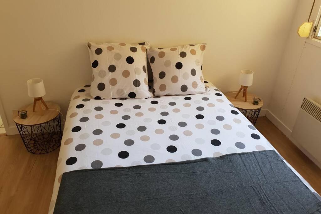 uma cama com lençóis de bolinhas e duas almofadas em Appartement plage de Trestraou em Perros-Guirec