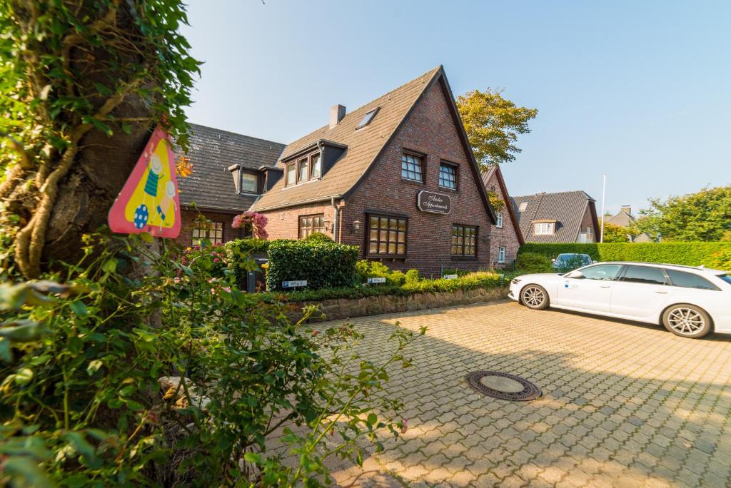 ein weißes Auto, das vor einem Haus parkt in der Unterkunft Auster-Appartements in Westerland