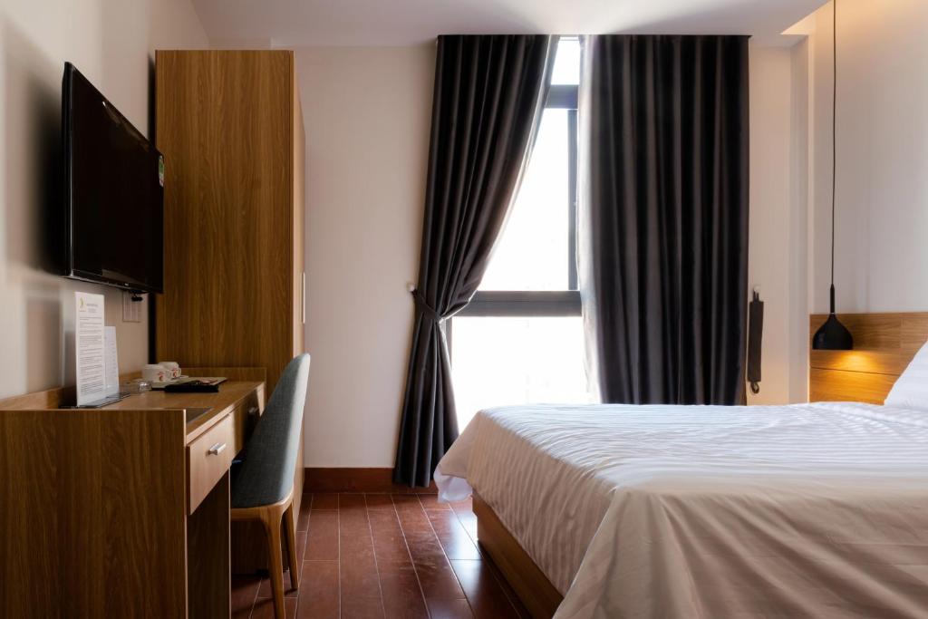 una camera d'albergo con letto, scrivania e finestra di Khang Điền Hotel a Thu Dau Mot