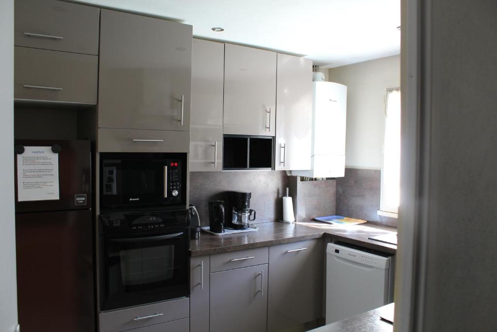 a kitchen with stainless steel appliances and white cabinets at Maison du Lavoir Disneyland in Bailly-Romainvilliers