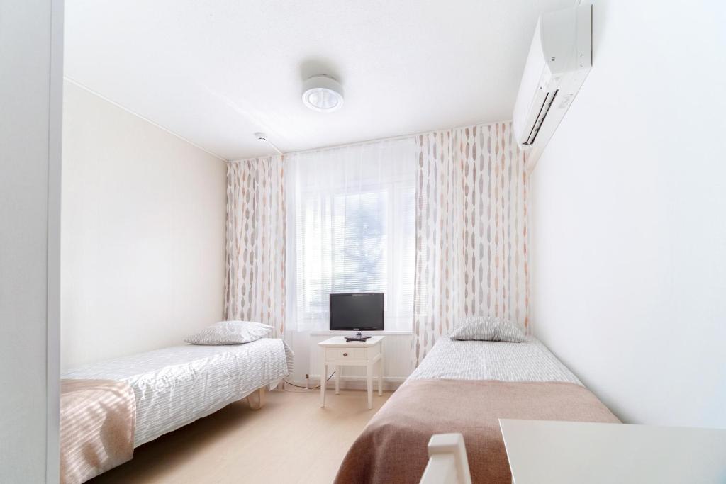 a white room with two beds and a tv at Motelli Marjaana in Kaustinen
