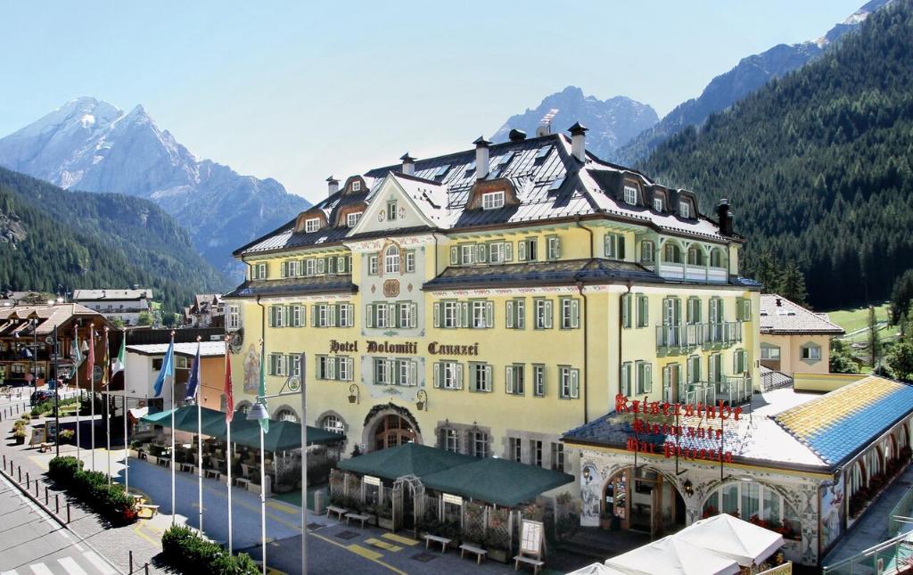 un grand bâtiment jaune au milieu d'une ville dans l'établissement Hotel Dolomiti Schloss, à Canazei