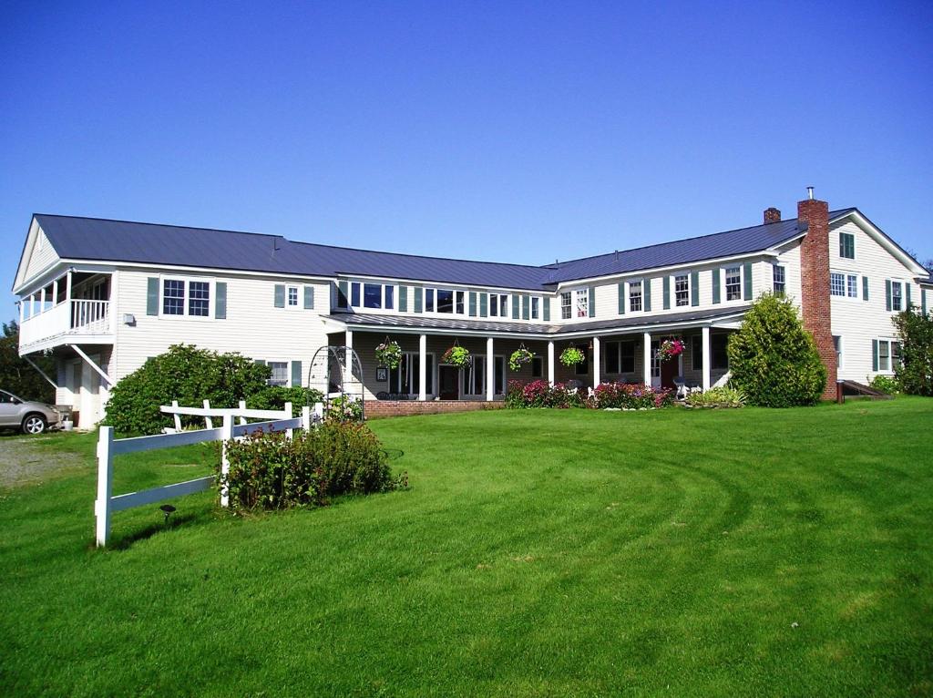 a large white house with a fence in the yard at Cooper Hill Inn in West Dover