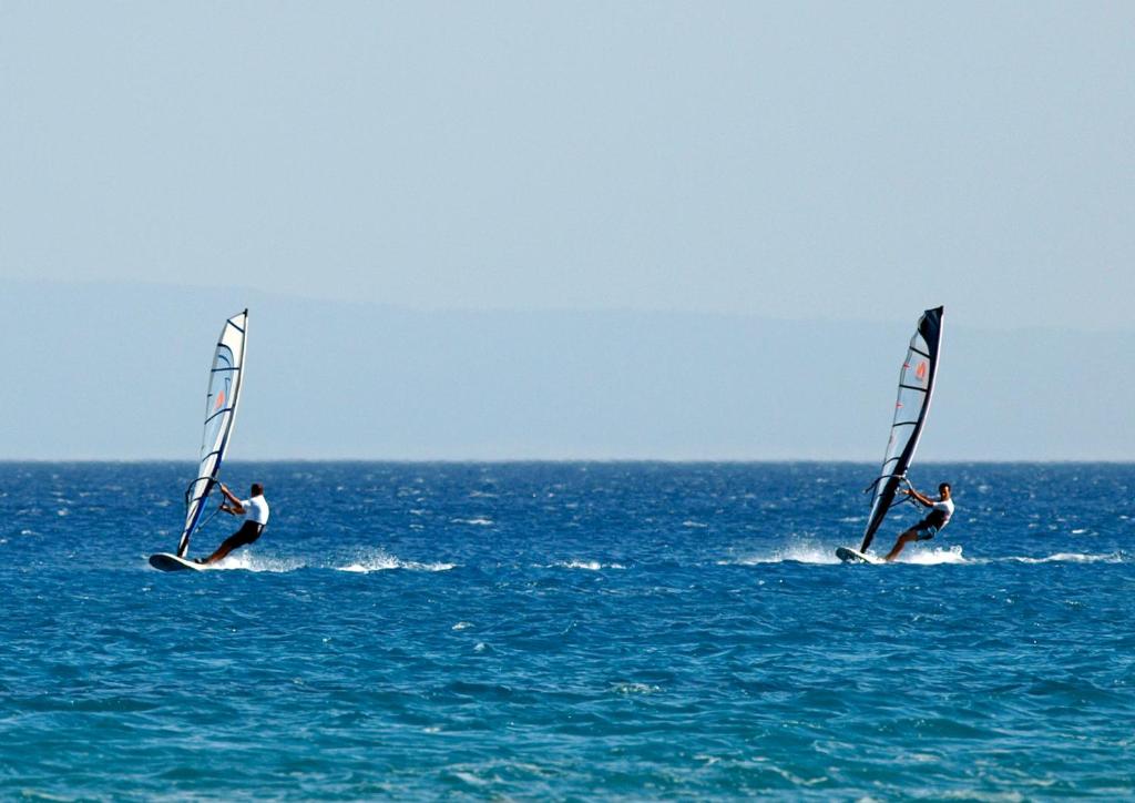 two people windsurfing in the ocean on the water at Cosmos Hotel in Vasiliki