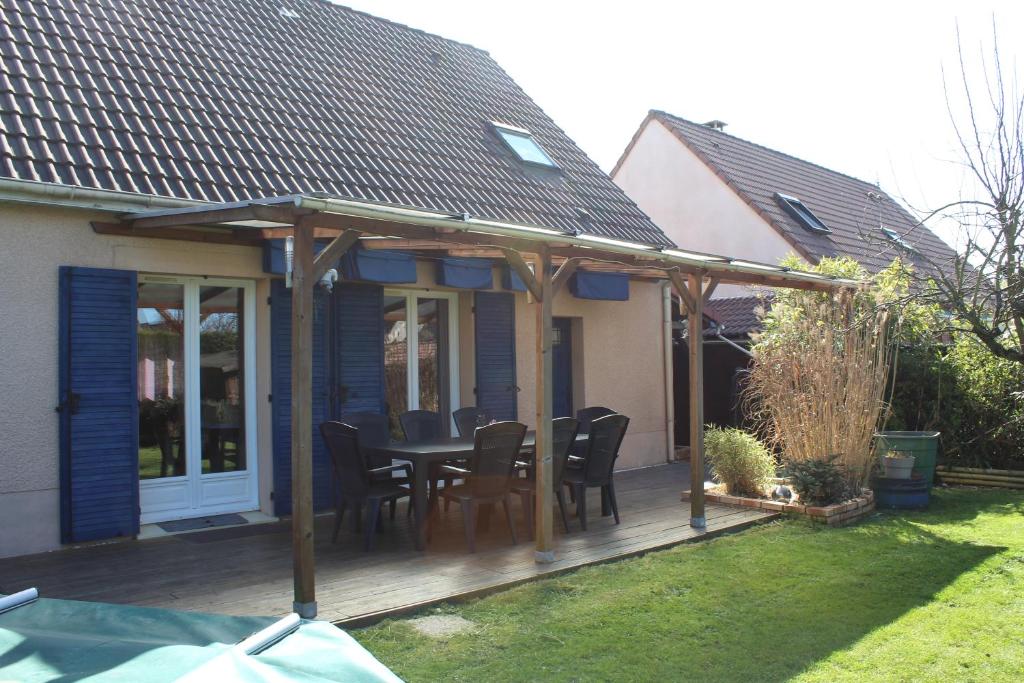 une terrasse en bois avec une table et des chaises. dans l'établissement Maison du Lavoir Disneyland, à Bailly-Romainvilliers