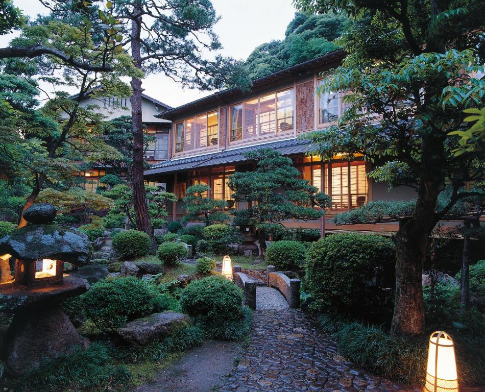 a garden in front of a building with trees and lights at Nishimuraya Honkan in Toyooka