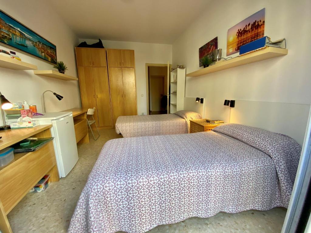 a hotel room with two beds and a desk at Barcelona Housing Student in Barcelona