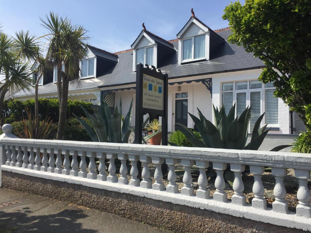 a white house with a white fence at Trewinda Lodge in Newquay