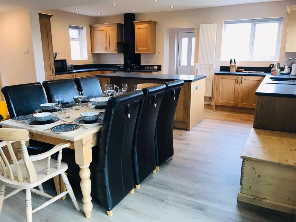 a kitchen with a wooden table with black chairs and a kitchen at Woodlands Cottage in York