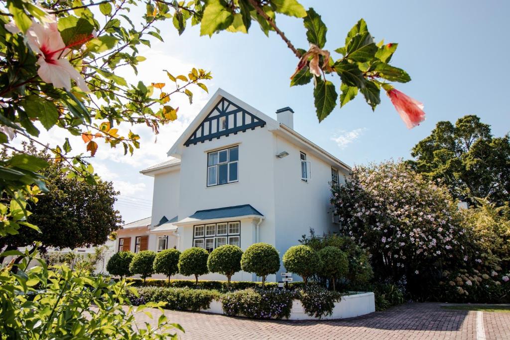 una casa blanca con arbustos delante en Whispering Oaks Guest House, en George