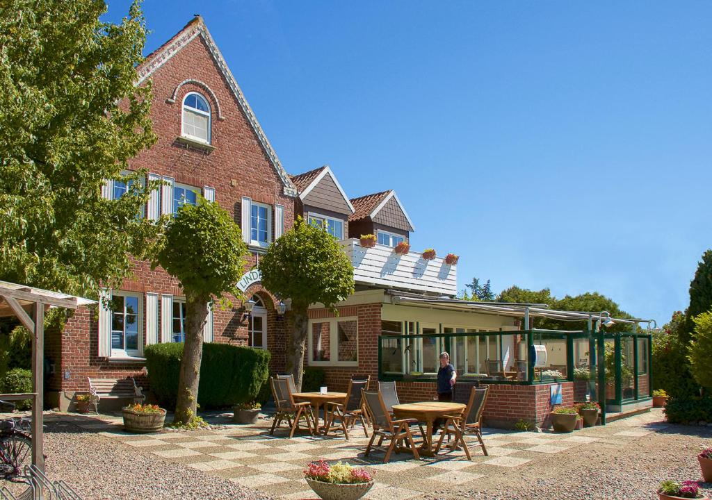 Eine Frau, die vor einem Gebäude steht. in der Unterkunft Lindenhof Hotel Garni in Sulsdorf auf Fehmarn