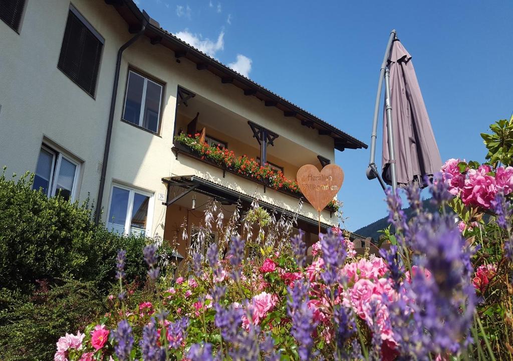 une maison avec un jardin fleuri devant elle dans l'établissement Pension Sonnenheim Rooms&Apartments, à Gmünd in Kärnten